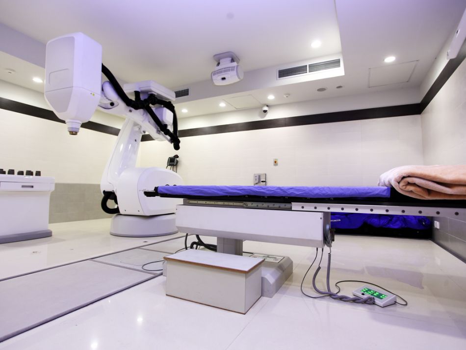 Untersuchungsraum mit Bestrahlungsgerät und Patientenliege.
