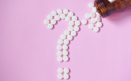 Tabletten als Fragezeichen vor pinkem Hintergrund 
