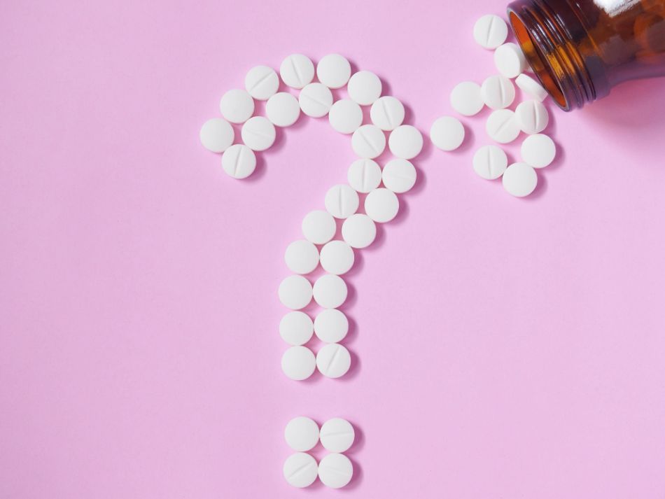 Tabletten als Fragezeichen vor pinkem Hintergrund 
