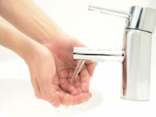 Frau wäscht ihre Hände unter fließendem Wasser.