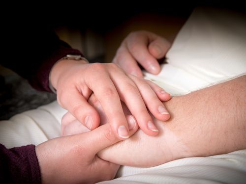 Angehöriger hält die Hände eines Patienten. Bild: Tobias Schwerdt © Krebsinformationsdienst, Deutsches Krebsforschungszentrum