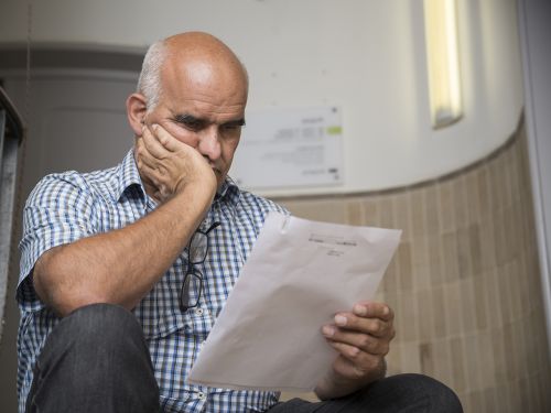 Patient sitz auf einer Treppe im Hausflur und liest besorgt einen Arztbrief, der seinen Krankheitsbefund beschreibt.