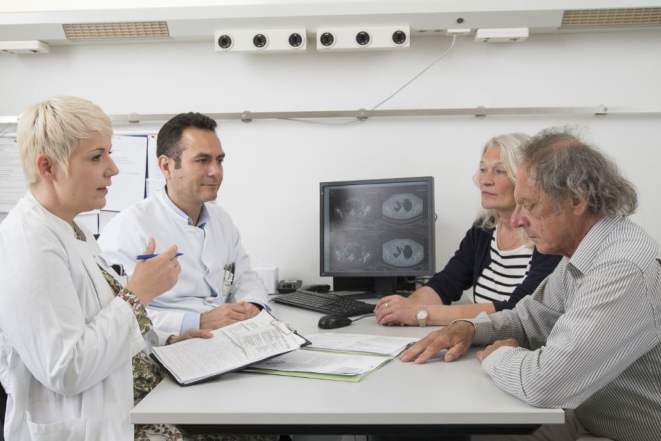 Ein Patient mit Lungenkrebs und seine Angehörige im Gespräch mit zwei Ärzten.