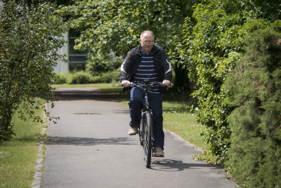 Älterer Mann fährt entspannt im Grünen Fahrrad. Foto: Tobias Schwerdt © Krebsinformationsdienst, Deutsches Krebsforschungszentrum
