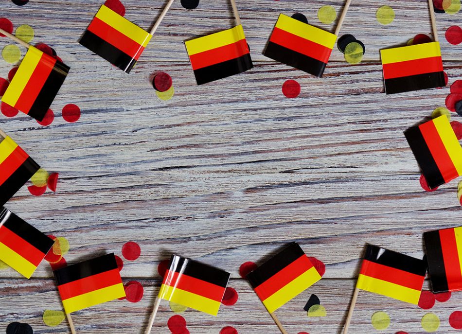 Kleine Deutschlandfahnen liegen auf einem Holztisch. © Irina Shamanaeva, Shutterstock