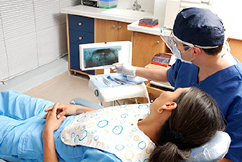 Patientlin liegt im Untersuchungsraum und begutachtet Röntgenaufnahme mit ihrem Zahnarzt. © oswaldoruiz, Pixabay