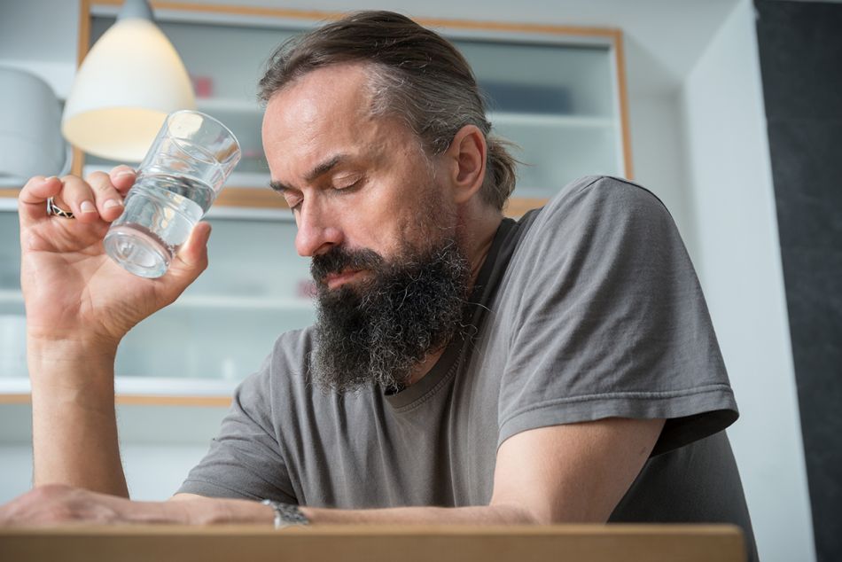 Ein Mann sitzt mit geschlossenen Augen und einem Wasserglas am Tisch. © Bild: Tobias Schwerdt © Krebsinformationsdienst, Deutsches Krebsforschungszentrum
