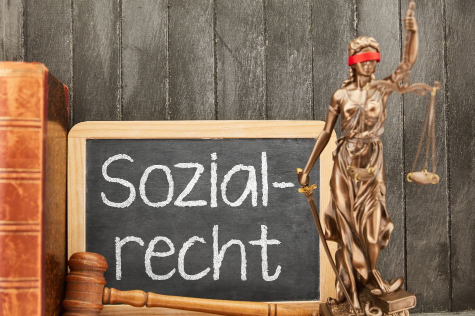 Tafel mit Aufschrift Sozialrecht neben Figur der Justizia mit roter Augenbinde