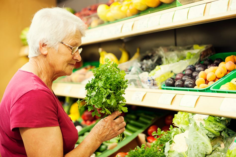 Seniorin kauft Gemüse im Geschäft ein. 