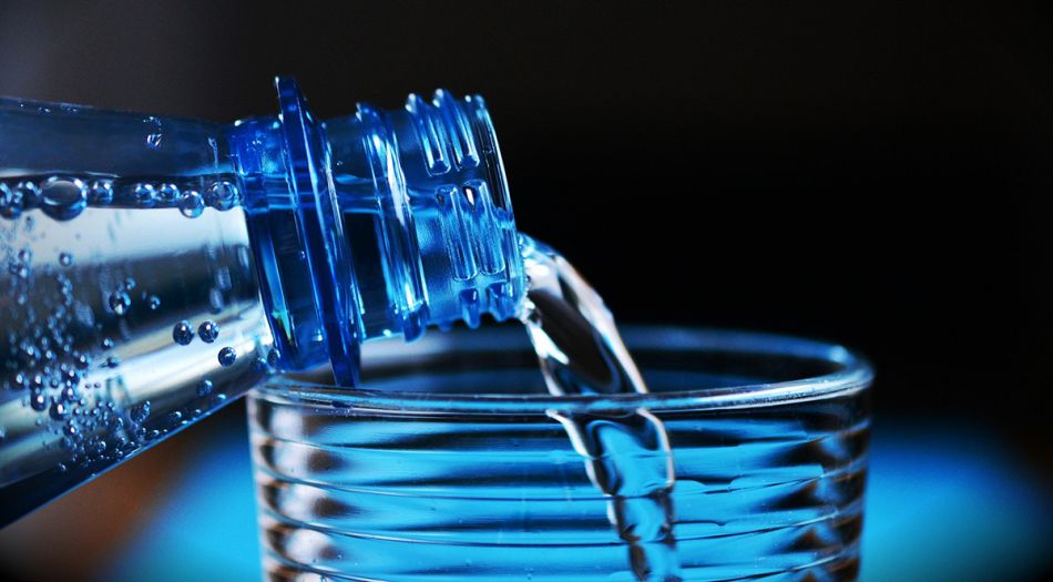 Wasser wird aus einer Flasche in ein Glas gefüllt. 