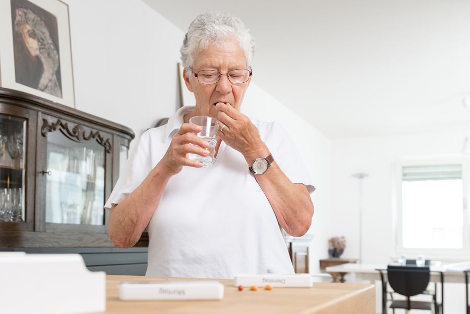 Ältere Dame nimmt Medikamente mit einem Glas Wasser ein. Bild: Tobias Schwerdt © Krebsinformationsdienst, DKFZ