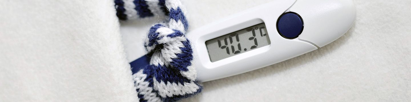 Fieberthermometer, das 40,3 Grad anzeigt, einen winzigen blau-weiß gestreiften Schal trägt und in einem winzigen weißen Bett liegt © congerdesign, Pixabay