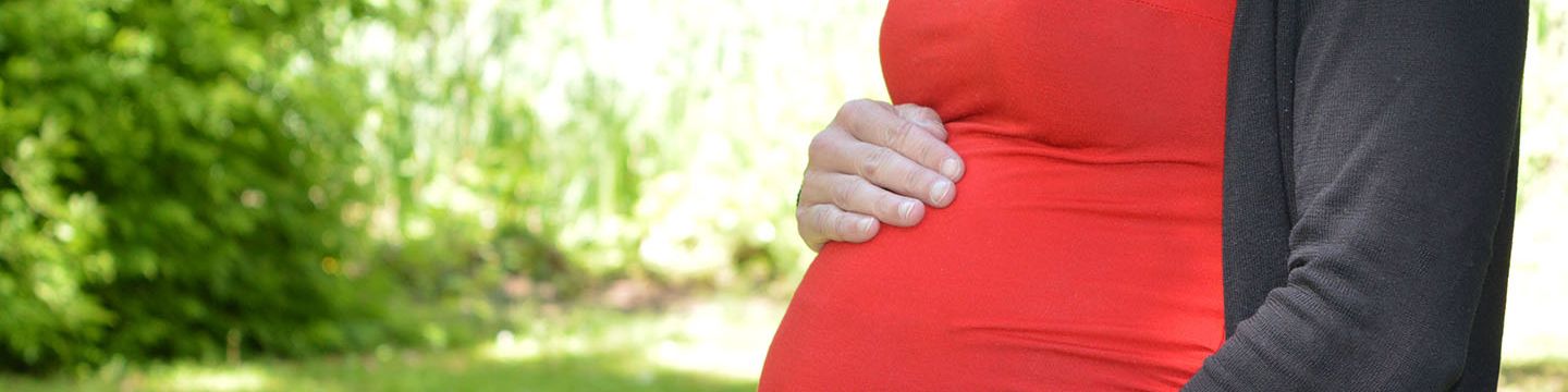 Eine schwangere Frau im roten T-Shirt streicht sich mit der Hand über den Bauch. © Krebsinformationsdienst, DKFZ