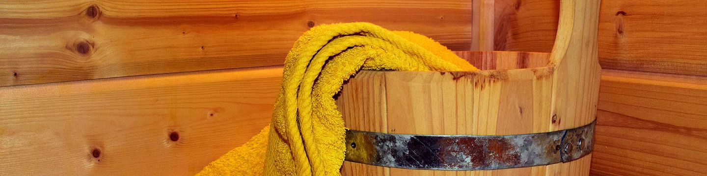 Wassereimer aus Holz, Holzschöpflöffel und gelbes Handtuch in einer Holzsauna © ulleo, Pixabay