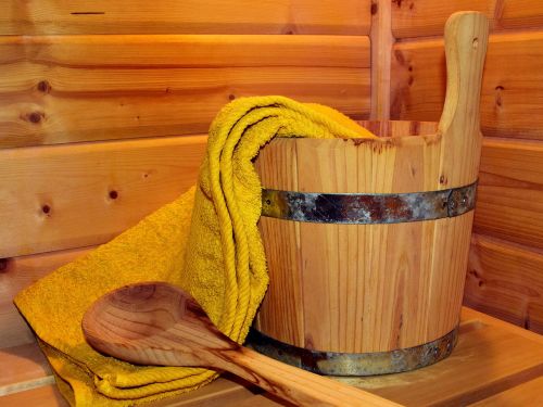 Wassereimer aus Holz, Holzschöpflöffel und gelbes Handtuch in einer Holzsauna © ulleo, Pixabay