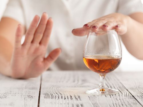 Ein Frau lehnt mit der Hand ein Glas Alkohol ab. © AndreyCherkasov, Shutterstock