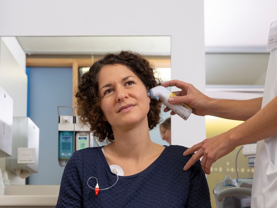 Patientin wird mit einem Infrarot-Thermometer Fieber gemessen. Bild: Tobias Schwerdt © Krebsinformationsdienst, DKFZ