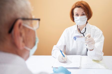 Ärztin und Arzt mit Mundschutz und Handschuhen in der Arztpraxis. © Aliaksandra Post, Shutterstock