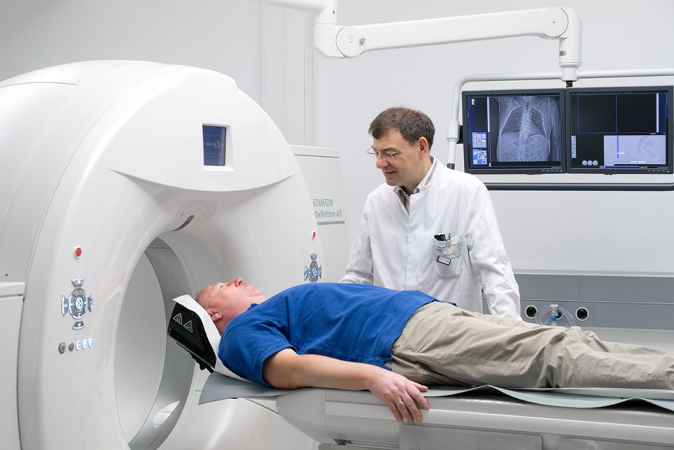 Mann liegt auf liege eines Computertomographen (CT) und spricht mit seinem Arzt. Foto: Tobias Schwerdt © Krebsinformationsdienst, DKFZ