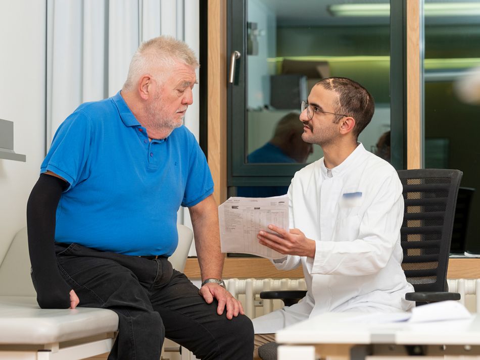 Arzt erklärt einem Mann auf einer Liege den Befund. © Krebsinformationsdienst, DKFZ