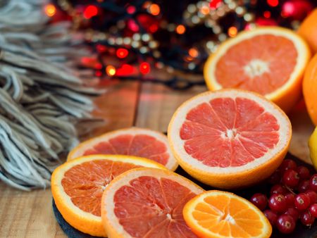 Grapefruits und Orangen vor weihnachtlichem Hintergrund