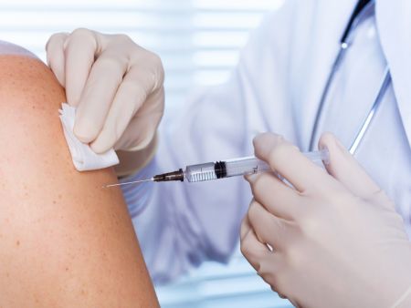 Eine Impfspritze sticht in den Oberarm