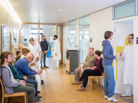 Mehrere Patientinnen und Patienten sitzen im Wartebreich einer Klinik.