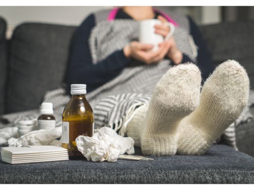 Frau mit Erkältung sitzt auf einem Sofa.