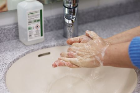 Person wäscht Hände mit Seife.