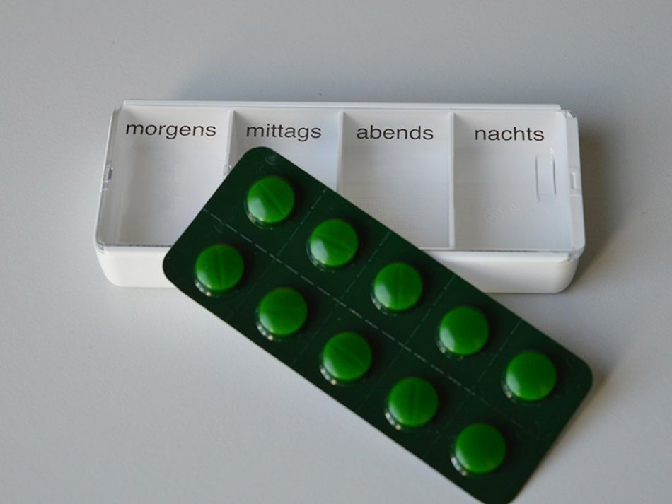 Blister mit Antihormontabletten liegt quer auf einem Tablettendispenser.
