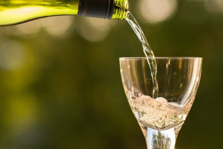 Weißwein wird in ein Glas eingeschenkt.
