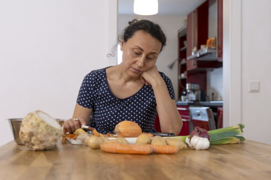 Eine Frau schneidet lustlos verschiedenes Gemüse.