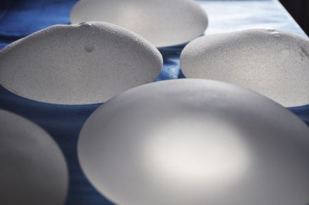Auf einem Tisch liegen mehrere Brustimplantate aus Silikon, die eine raue Oberfläche haben.