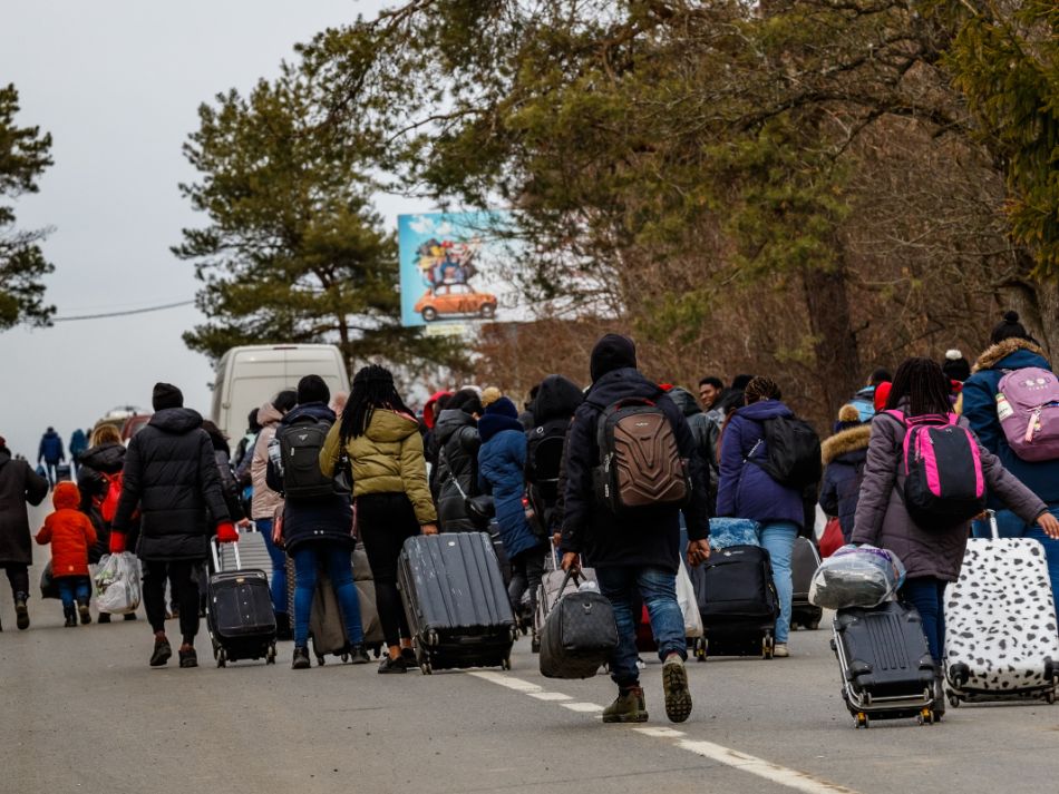 Eine Gruppe ukrainischer Flüchtlinge gehen bepackt mit Koffern eine Straße entlang