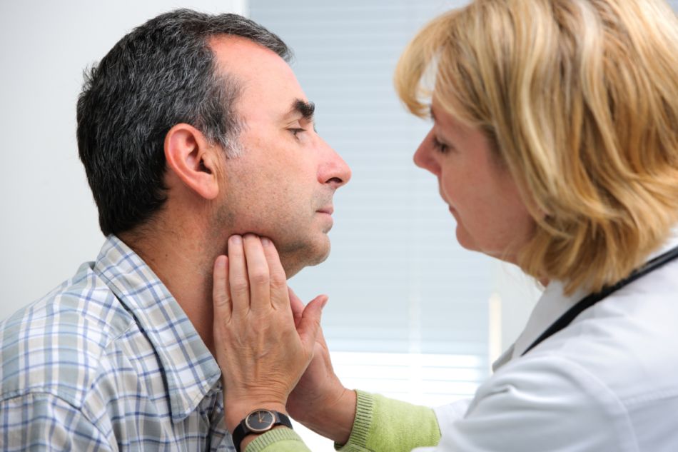 Eine Ärztin tastet zur Diagnose von Schilddrüsenkrebs den Hals eines Patienten ab.