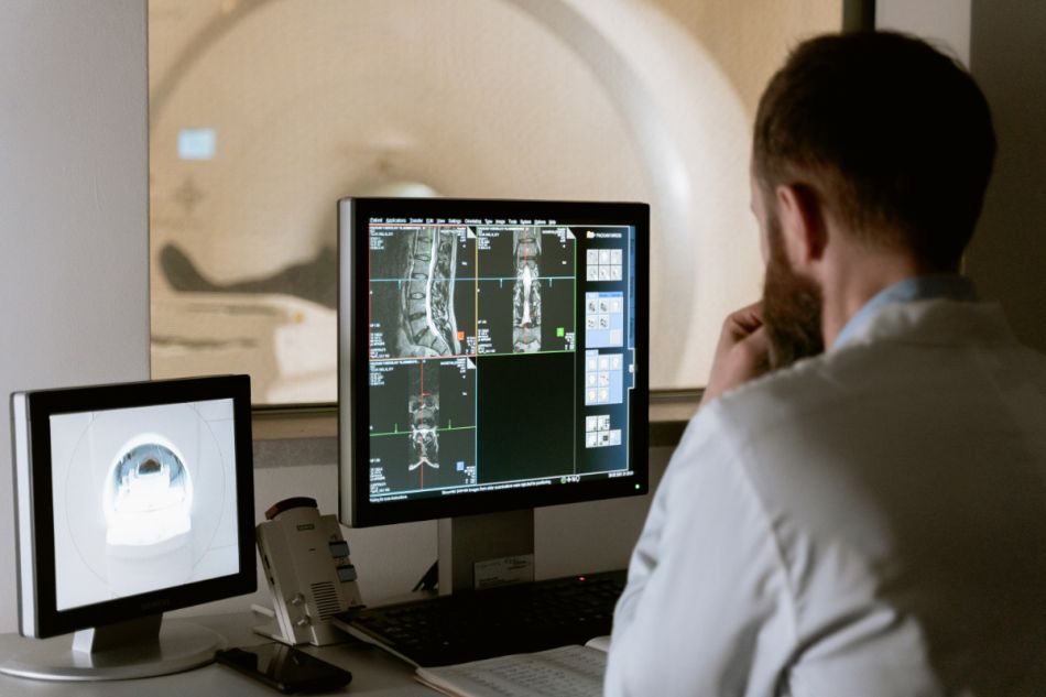Ein Arzt sitzt vor einem Bildschirm und betrachtet MRT-Aufnahmen.