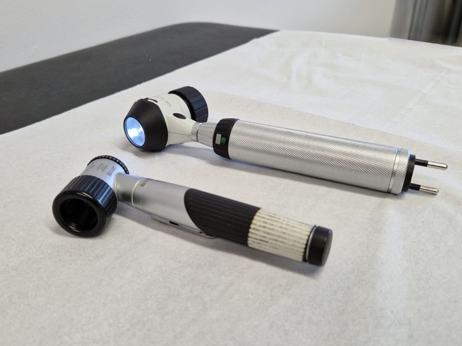 Zwei verschiedene Auflichtmikroskope (Dermatoskop) liegen auf einer Untersuchungsliege.