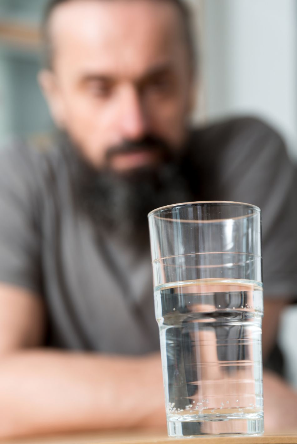 Wasserglas mit Krebspatient im Hintergrund