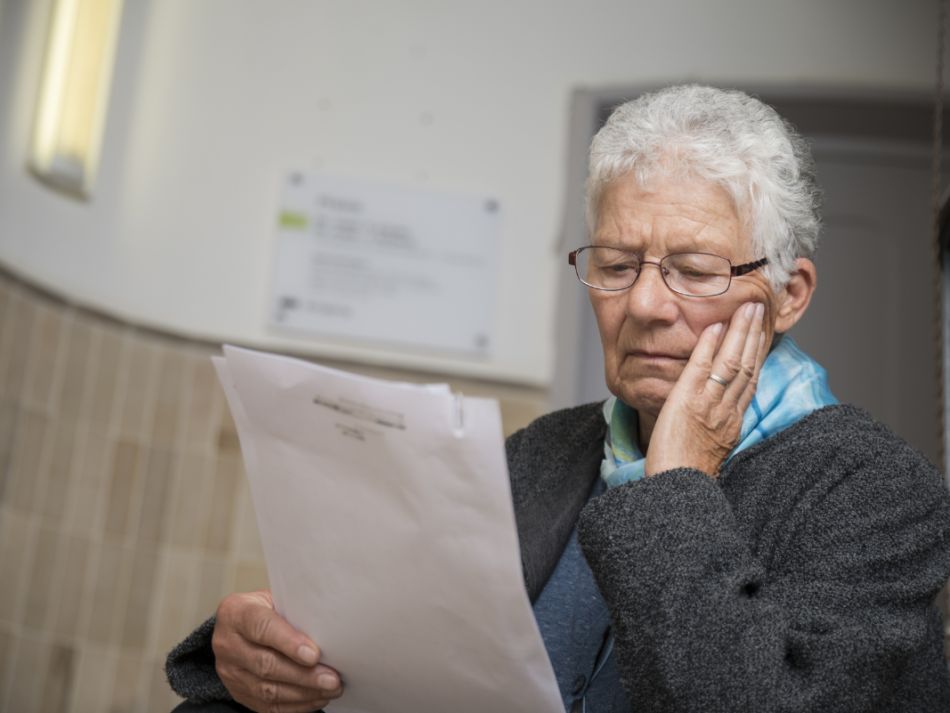 Eine ältere Dame liest ein Schreiben und wirkt erschüttert