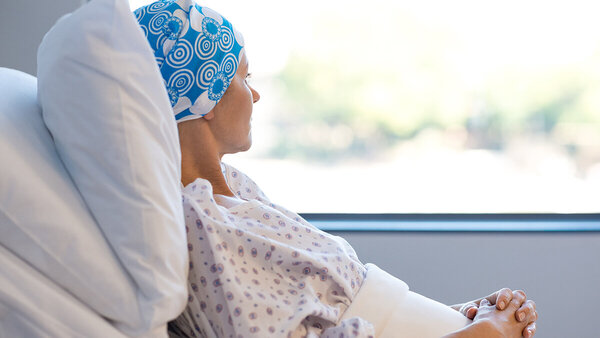 Frau mit Kopftuch in einem Krankenhausbett