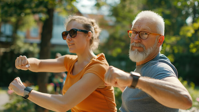 Ein älterer Mann und eine Frau bei Fitnessübungen im Freien.