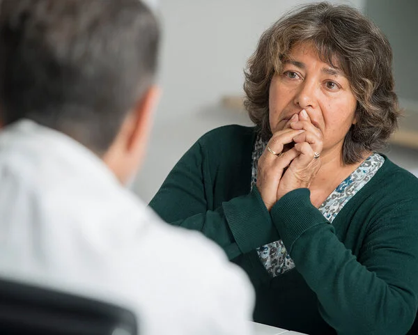 Patientin hält ihre Hände vor den Mund, während sie mit ihrem Arzt ihre Diagnose bespricht. Foto: Tobias Schwerdt