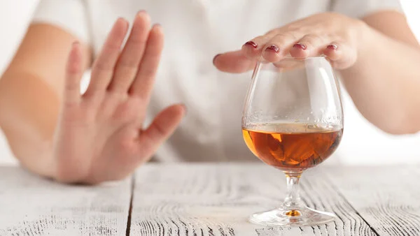 Ein Frau lehnt mit der Hand ein Glas Alkohol ab., © AndreyCherkasov, Shutterstock Ein Frau lehnt mit der Hand ein Glas Alkohol ab.