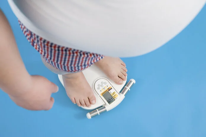 Körpergewicht, © Whitetag, Thinkstock Perspektive von oben: Mann mit größerem Bauchumfang steht auf einer Waage und wiegt sich.