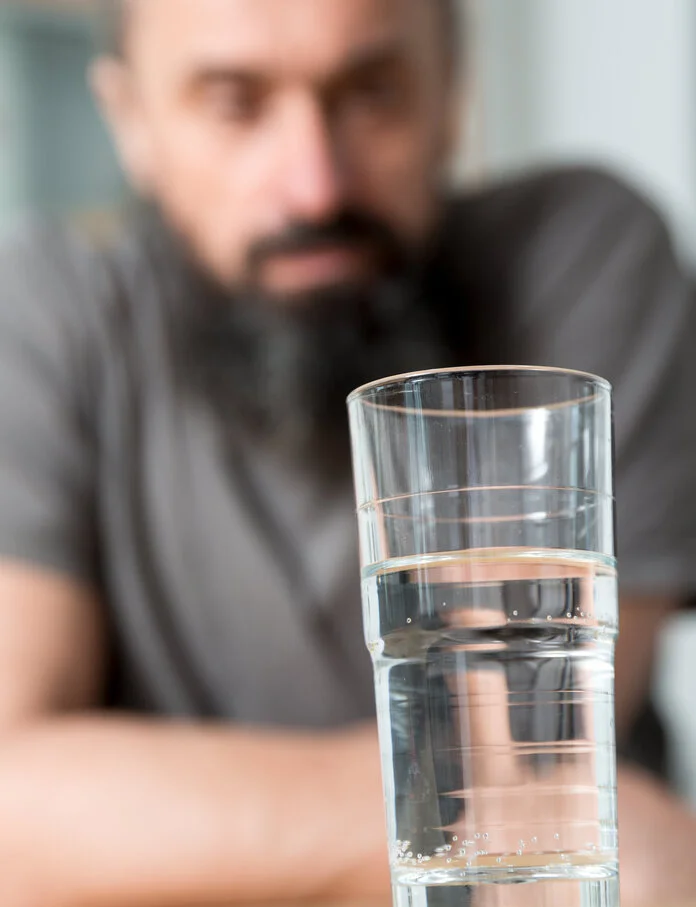 Wasserglas, © Krebsinformationsdienst, DKFZ; Foto: Tobias Schwerdt Wasserglas mit Krebspatient im Hintergrund