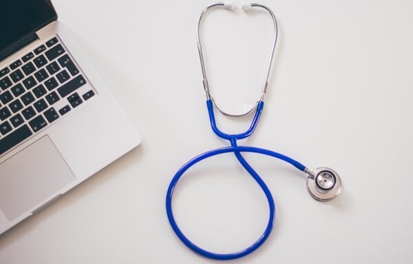 Stethoskop liegt neben aufgeklapptem Laptop