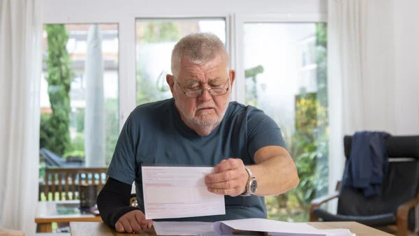 Unterlagen sortieren, © Krebsinformationsdienst, DKFZ; Foto: Tobias Schwerdt Ein älterer Herr sitzt am Esstisch und ordnet Unterlagen.