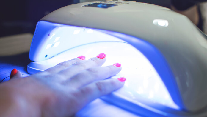UV-Nagellampe, irrmago, freepik Eine Hand mit dekorierten Nägeln unter einer UV-Nagellampe