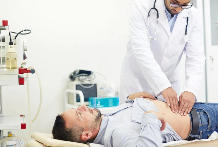 Abtasten, © Pressmaster, Shutterstock.com Ein Arzt tastet einem Mann auf einer Untersuchungsliege den Bauch ab.