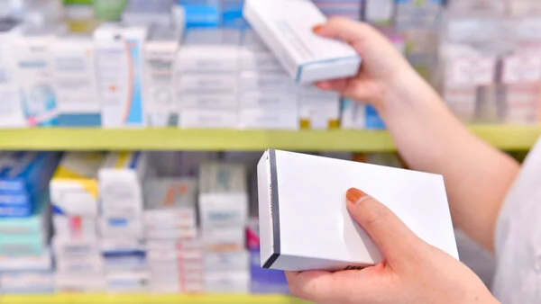 Arzneimittel aus der Apotheke, © I-Viewfinder, Thinkstock Die Hände einer Apotheken-Mitarbeiterin nehmen 2 Arzneimittelpackungen aus dem Apothekenregal